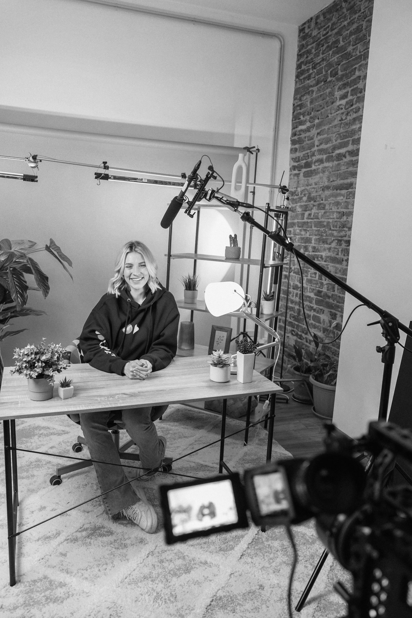 Videographer on a studio video set with lighting rigs, a boom microphone, and a camera in the foreground.